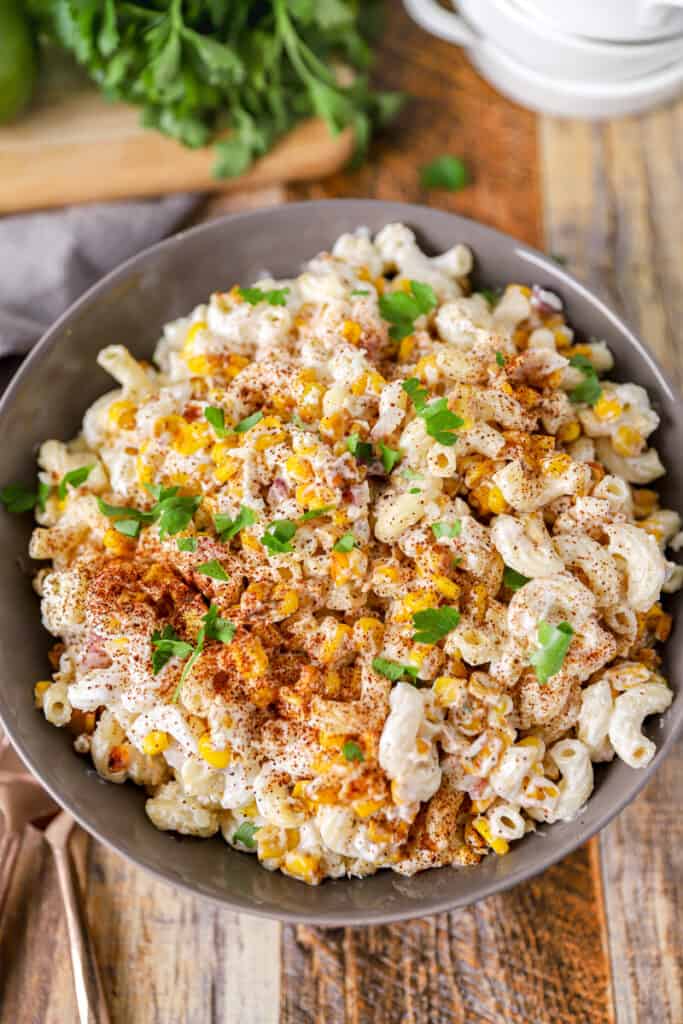 overhead shot of the Mexican corn pasta salad topped with parsley on a wood surface, 