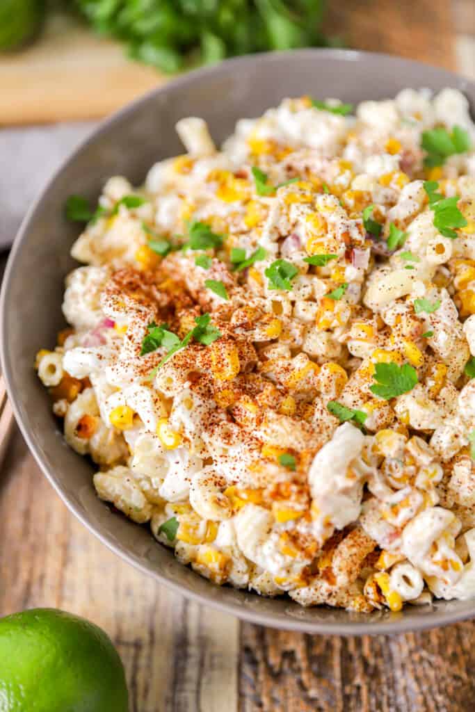 Mexican corn pasta salad on a wood surface in a grey bowl.