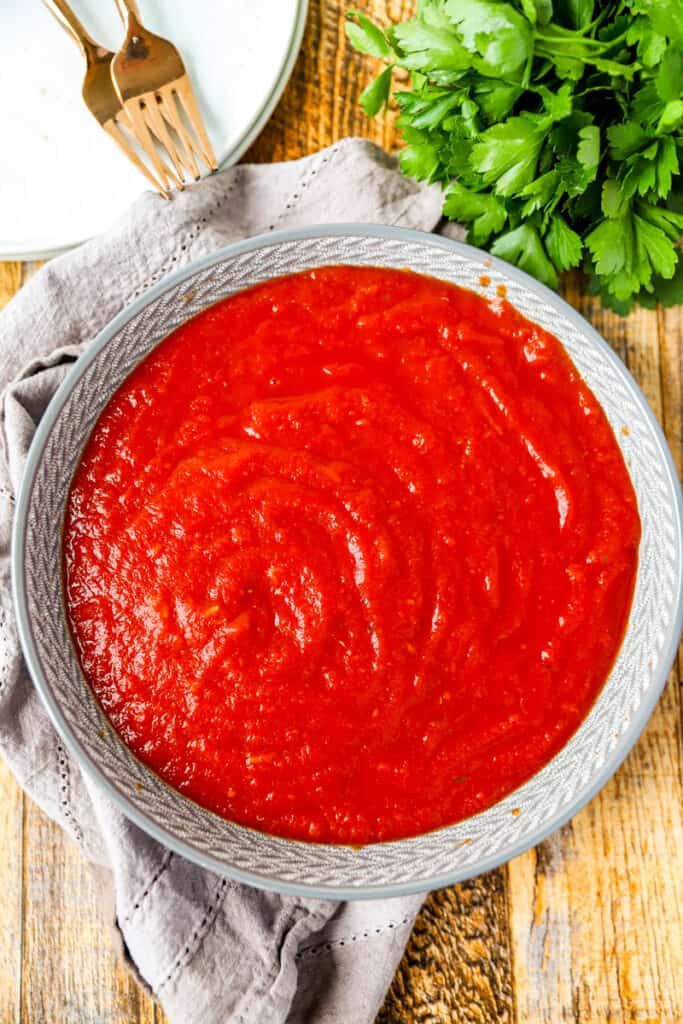 overhead photo of the grey bowl filled with the spaghetti sauce on a wood surface.