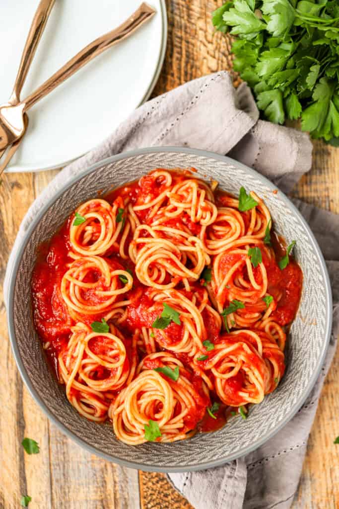 overhead photo of the spaghetti swirls in the smooth spaghetti sauce on a wood surface.