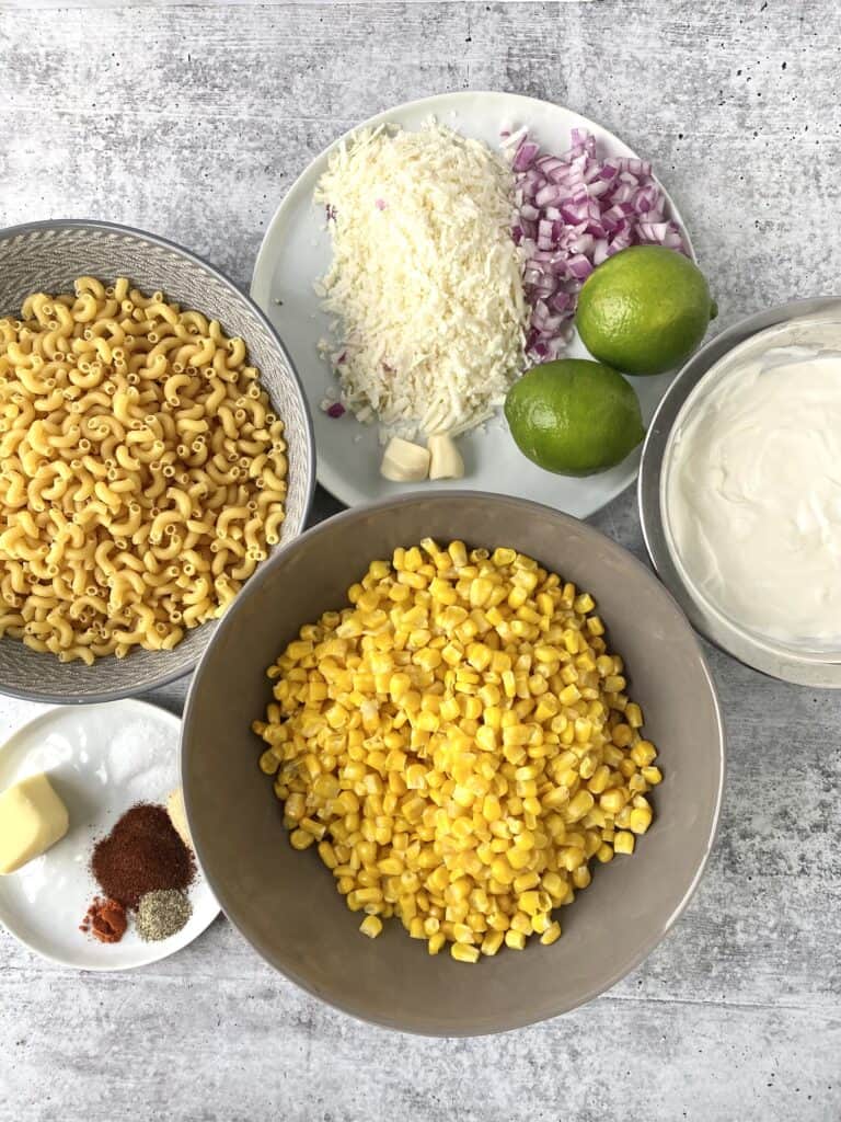 overhead shot of the ingredients: noodles, Cotija, limes, corn, crema and sour cream, garlic, red onions, butter, salt, pepper, chili powder, cayenne pepper, garlic powder.