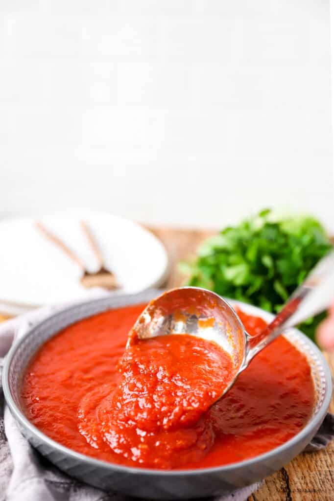 close photo of a ladle spooning some of the sauce in a bowl full.