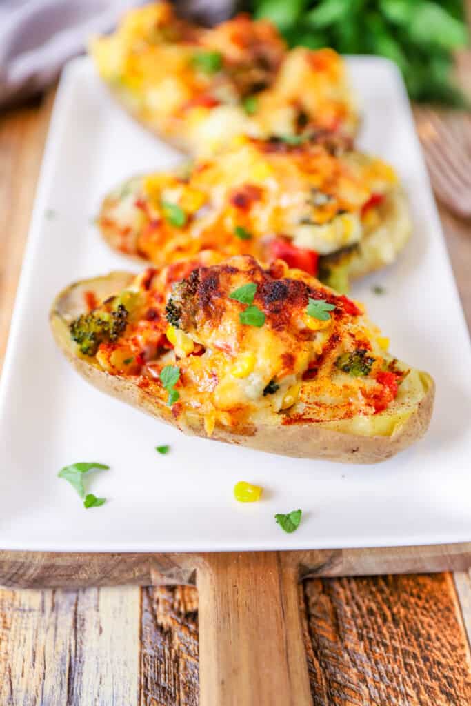 the veggie stuffed potatoes on a white dish on a wood surface.