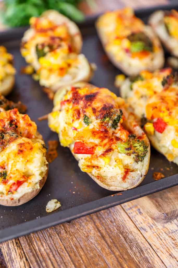 veggie twice baked potatoes on a baking sheet on a wood surface.