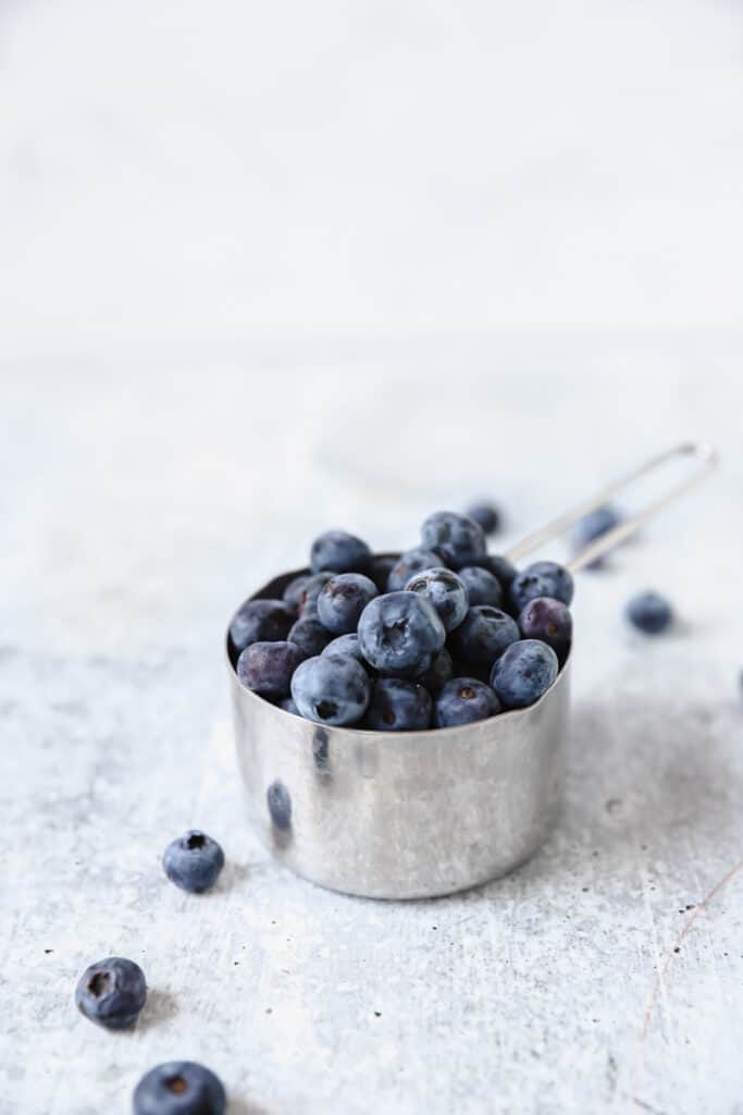 silver measuring cup filled with fresh blueberries.