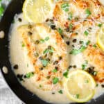 overhead shot of the creamy chicken piccata in a pan with lemon slices.