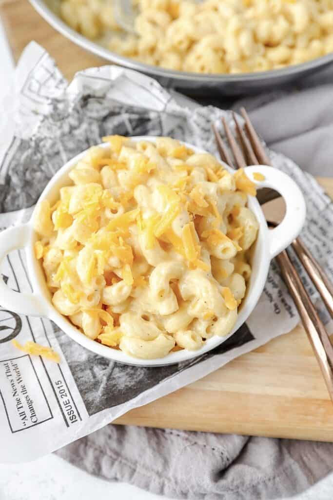 the creamy mac and cheese topped with shredded cheese in a white dish