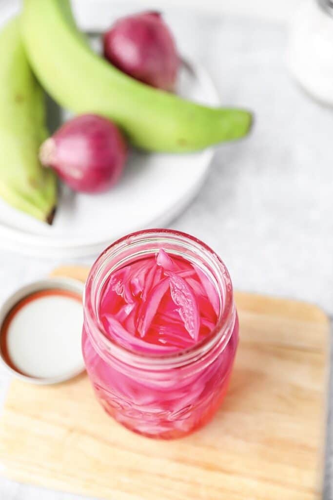 overhead shot of the pickled red onions on a wood board.