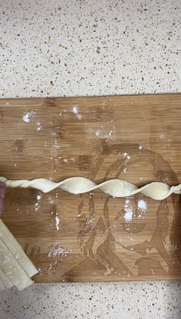 overhead shot showing one puff pastry strip twirled into a corkscrew shape.