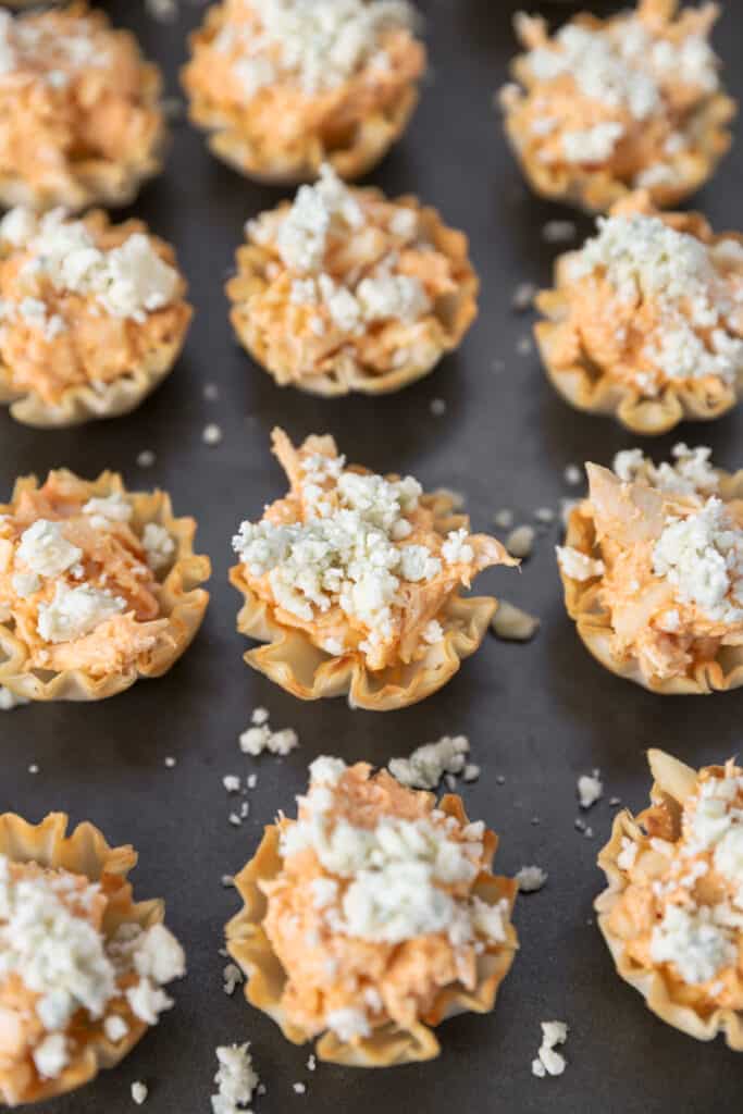 the filled phyllo cups now topped with blue cheese on a baking sheet.