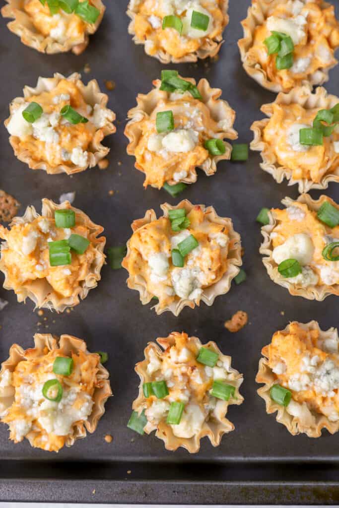 the baked buffalo chicken bites on a baking sheet topped with scallions