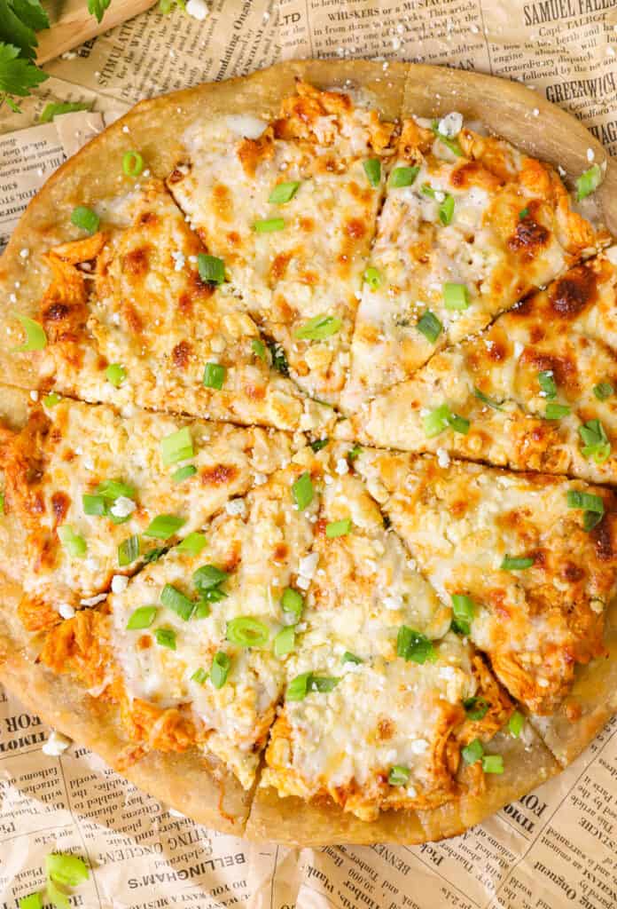 overhead shot of the full pizza sliced on brown newsprint paper.