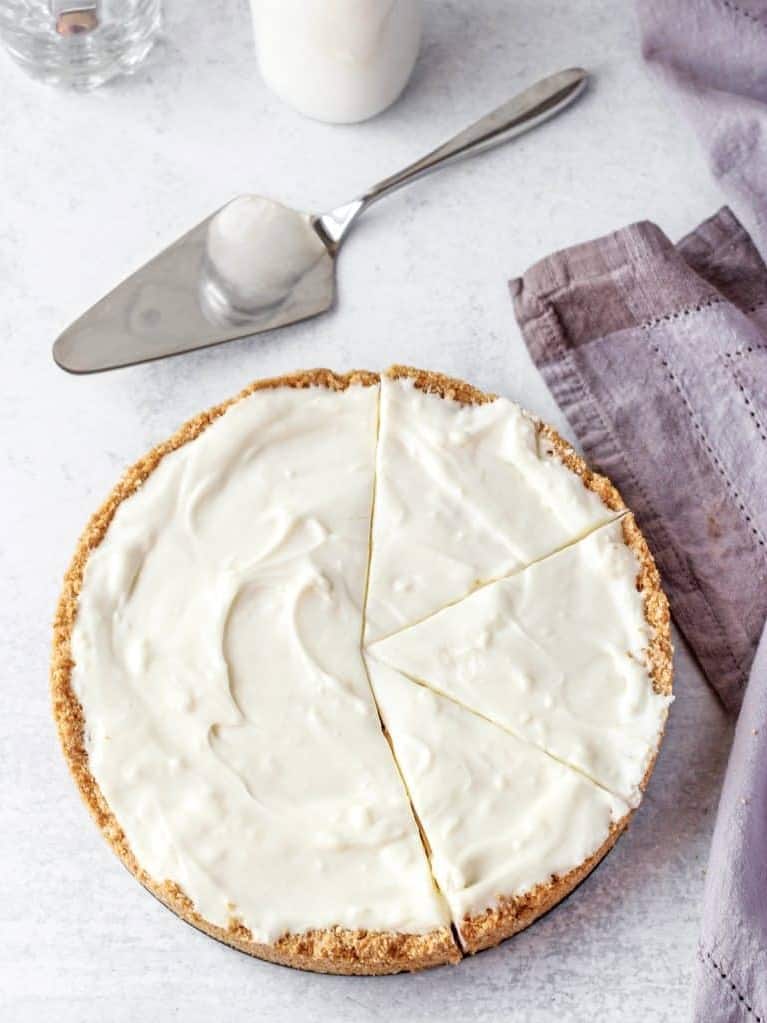 overhead shot of the coconut cheesecake with half cut into slices. Pie cutter to the side.