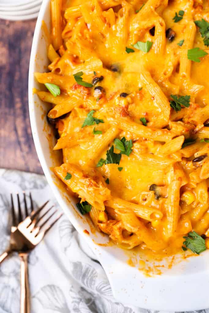 overhead shot of the chicken fajita pasta in the white casserole fish on a wood surface with 2 forks.