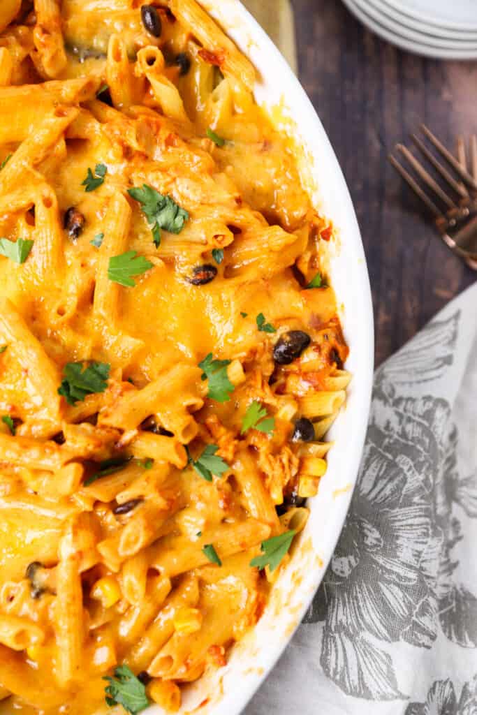 overhead shot of the chicken fajita pasta in the white baking dish on a wood surface.