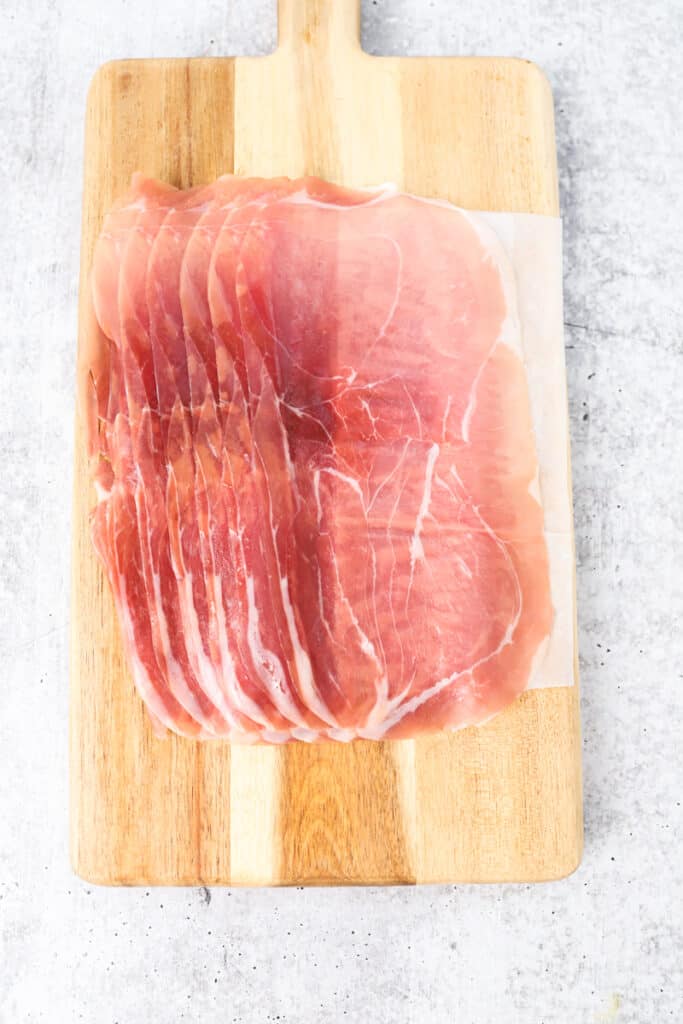 slices of prosciutto on a wood cutting board