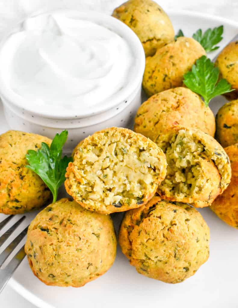 air fryer falafel on a white plate with one falafel cut open showing interior texture.