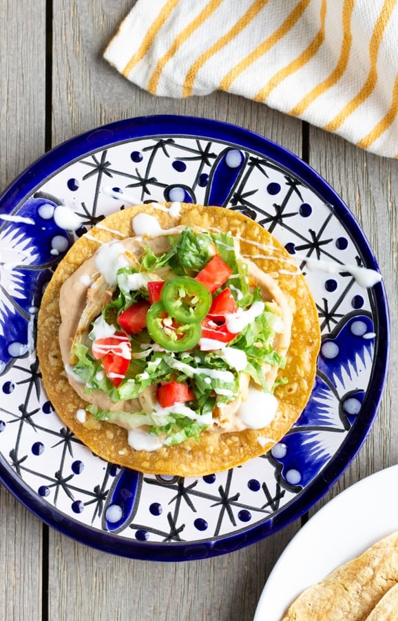 overhead shot of rotisserie chicken tostadas on a blue pattern plate