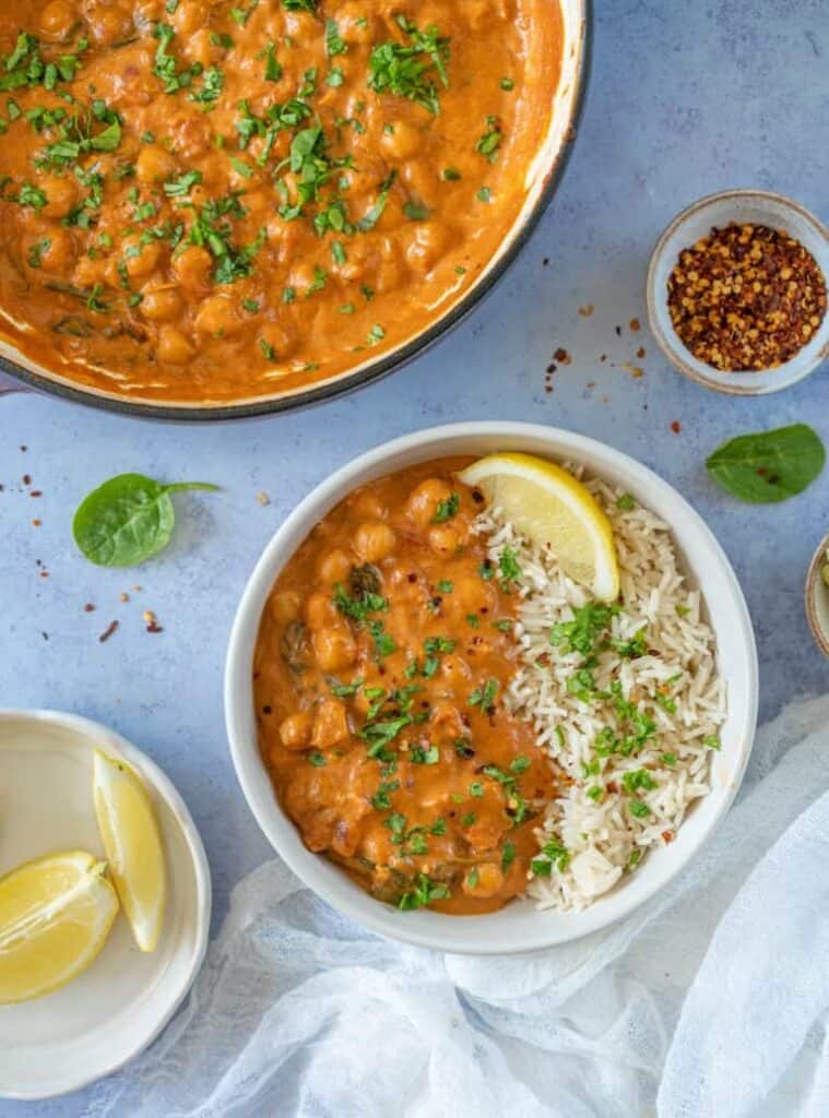 overhead shot of chickpea curry in white bowls with lemon wedges.