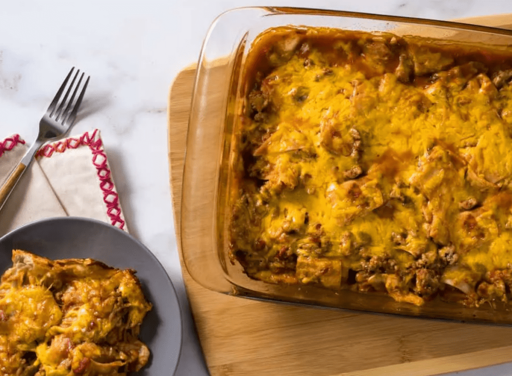 overhead shot of turkey taco casserole in a baking dish on a wood cutting board.