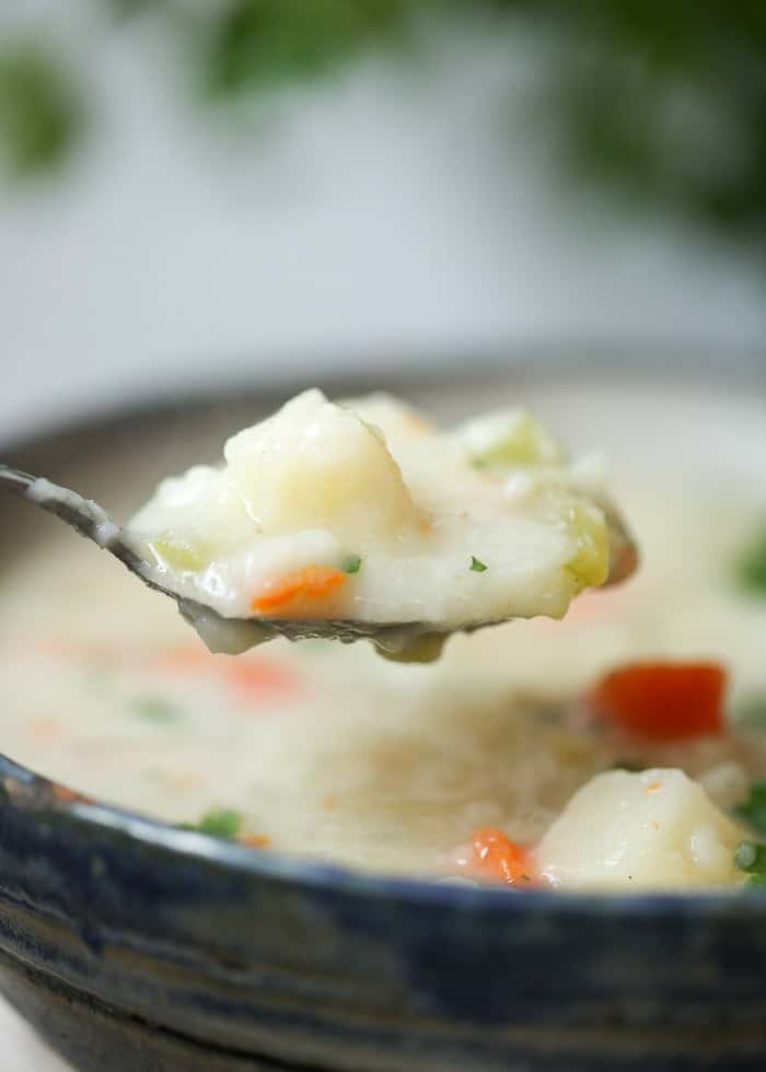 a spoon scooping the potato soup from the bowl.