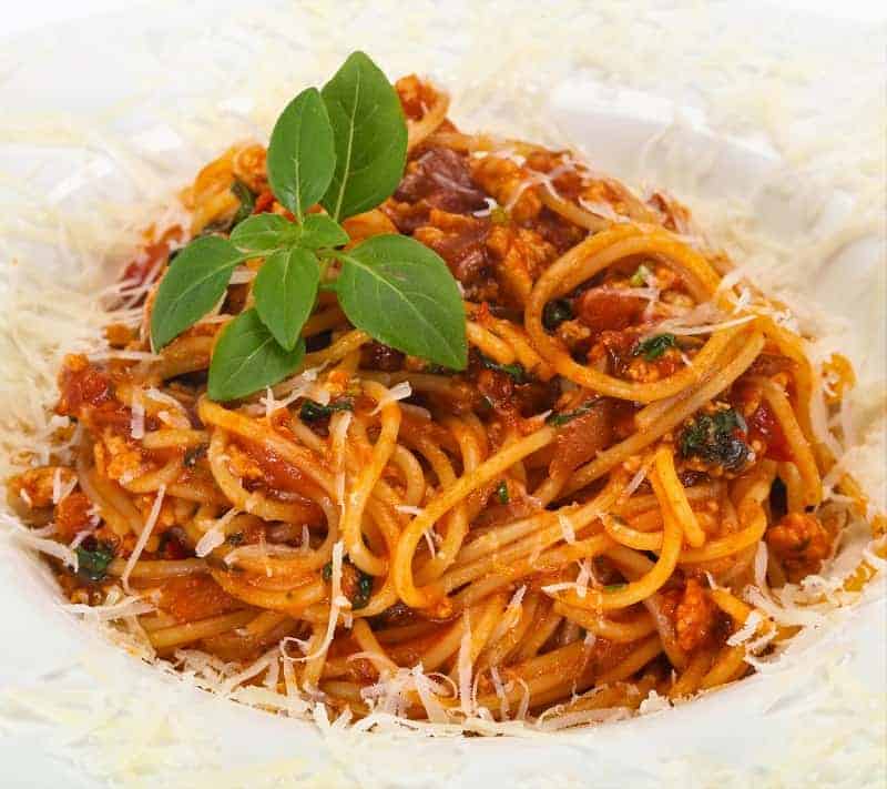 turkey bolognese on spaghetti in a white bowl.