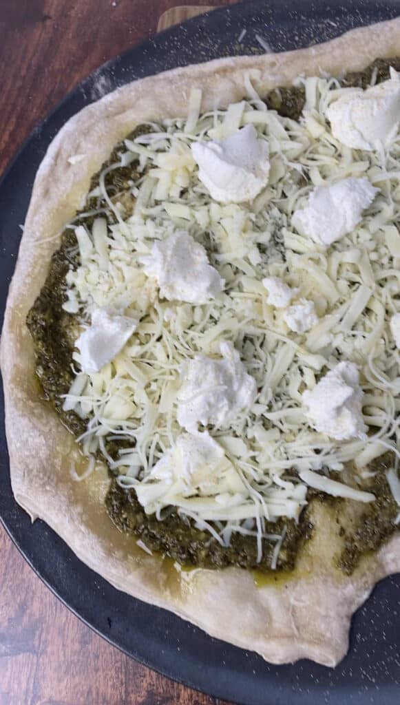 the unbaked pizza topped with all the cheese and dollops of ricotta.