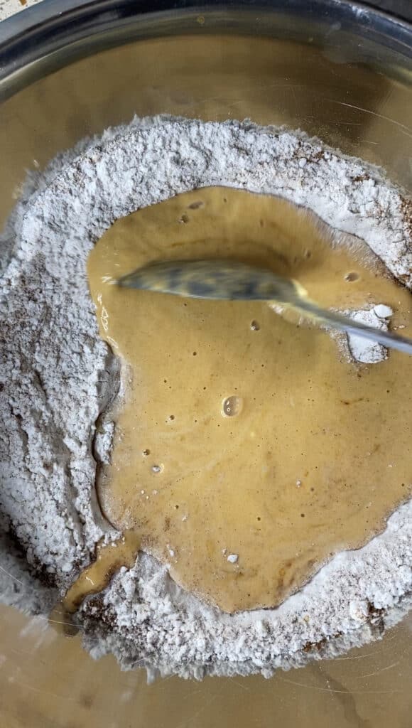 overhead shot of the dry and wet ingredients mixing together in a silver mixing bowl