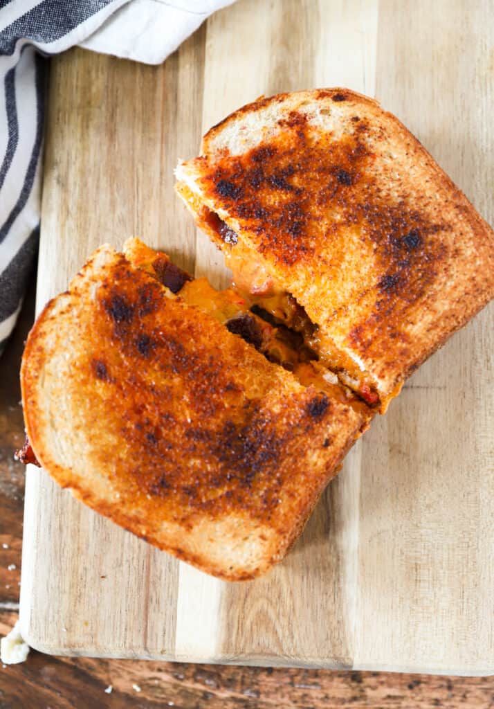 overhead shot fo the grilled cheese cut in half on a wood cutting board.