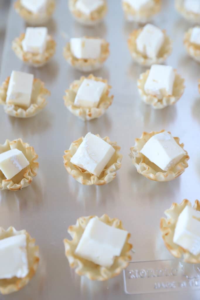 the phyllo shells with a wedge of Brie cheese in them on the baking sheet.