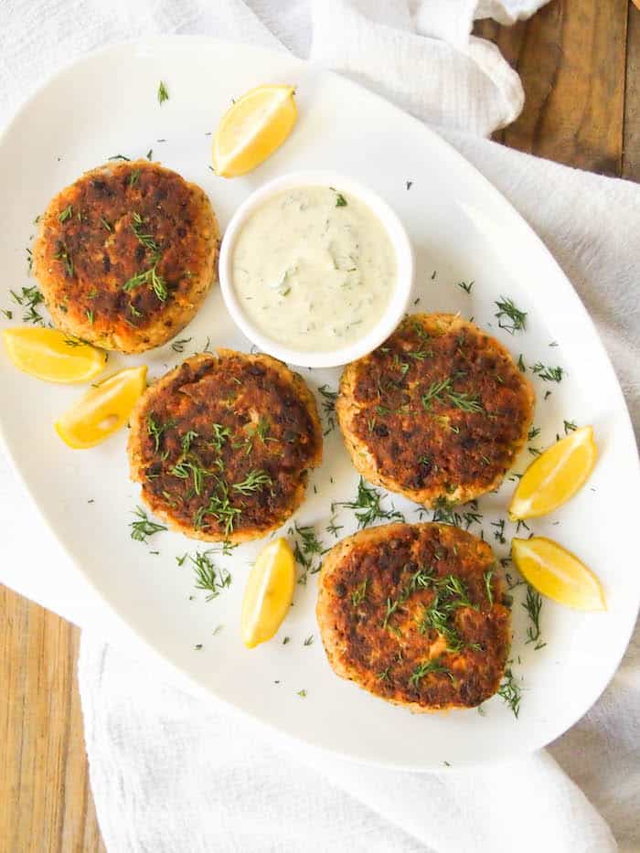 overhead shot of the salmon patties with lemon wedges on a white serving platter.