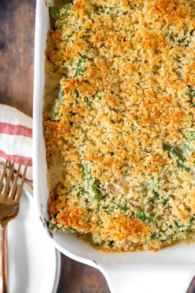 overhead shot of the green bean casserole in a white baking dish on a wood surface.