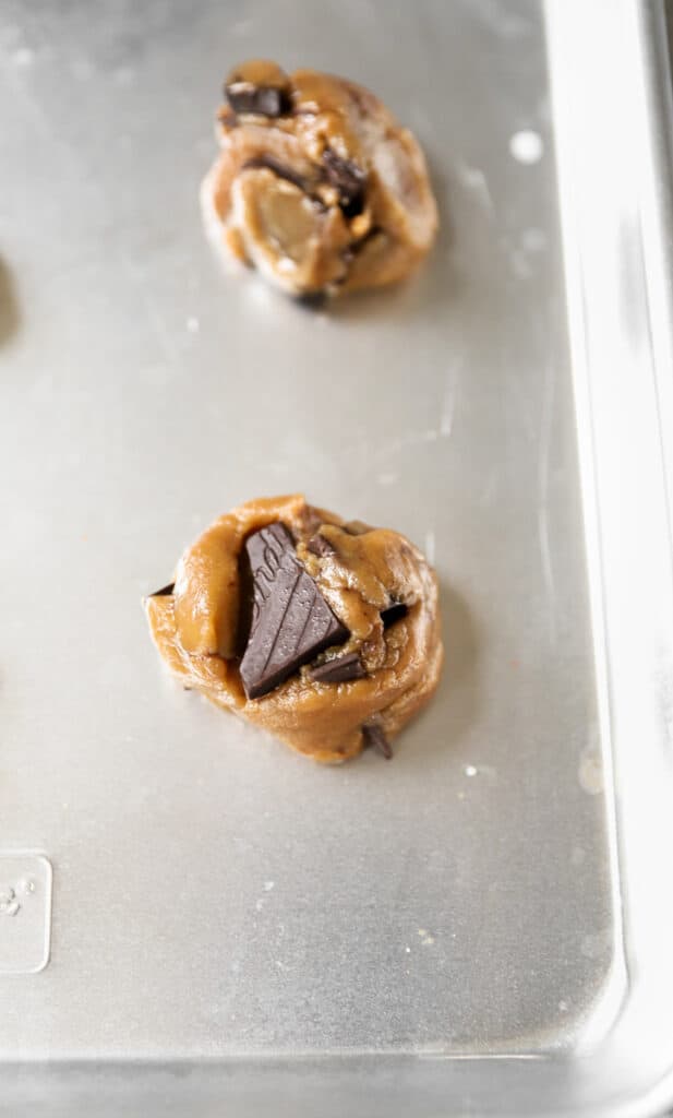 the raw cookie dough ball on the silver baking sheet.