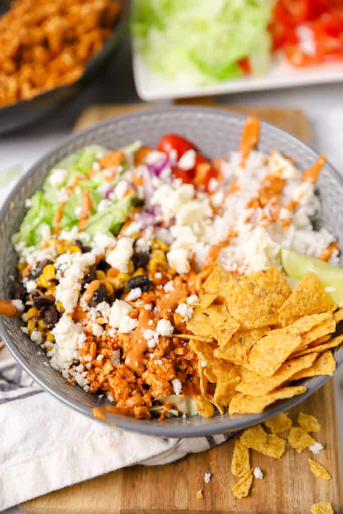 an assembled chicken burrito bowl drizzled with chipotle sour cream on a wood cutting board.