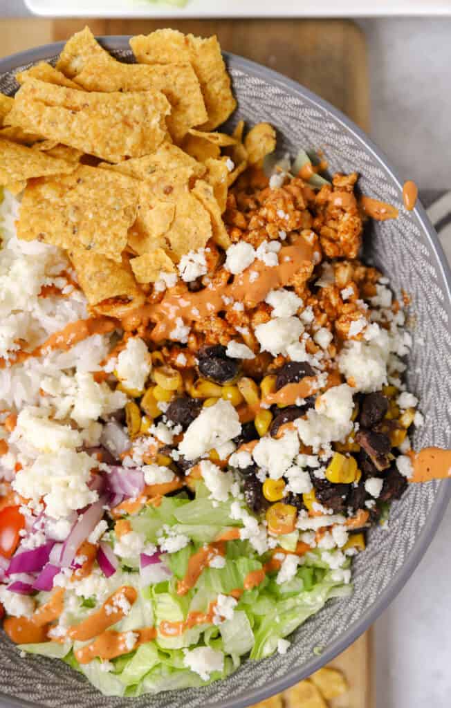 chicken burrito bowl topped with crushed tortilla chips in a grey bowl