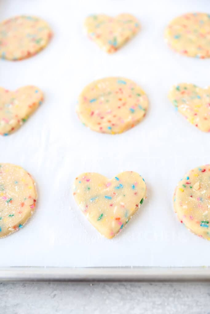 circle and heart shaped cookies on the parchment paper lined baking sheet before baking.