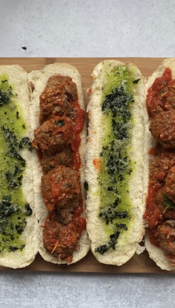 overhead shot making the meatball parms showing the open-faced sandwiches with the basil garlic butter on one side and the meatballs on the other.