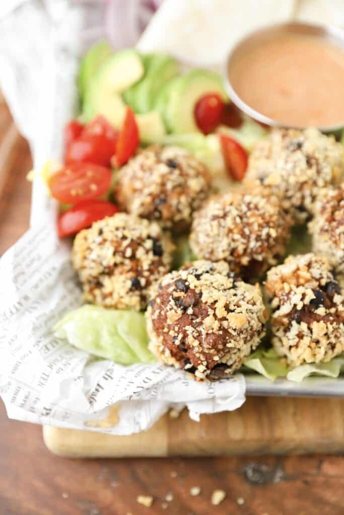 taco meatballs after baking on white newsprint paper on a silver tray. 