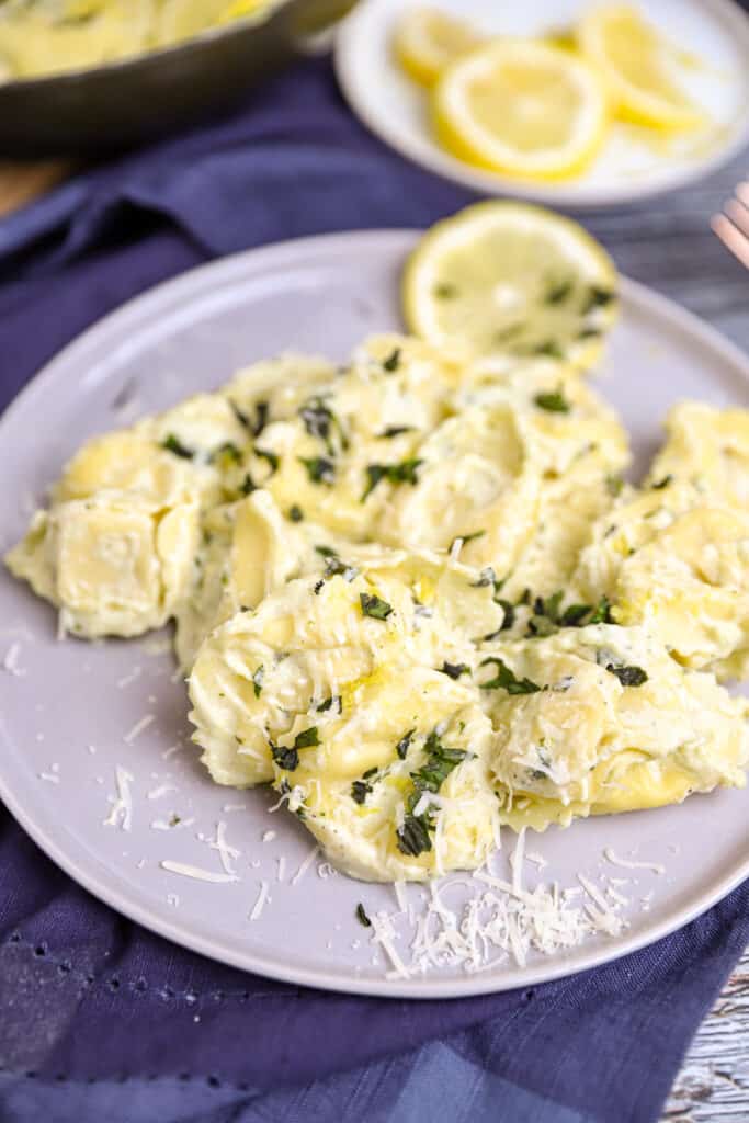 the tortellini on a grey round plate, s plate of lemons in the back.