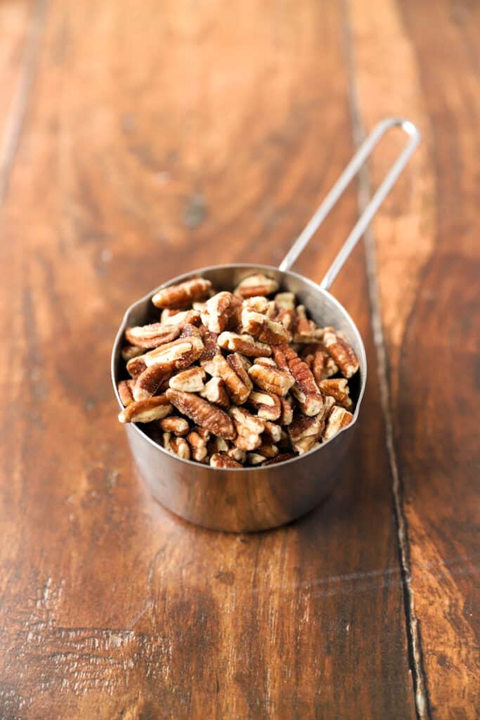 a silver measuring cup filled with chopped pecans