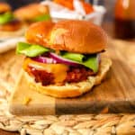 bbq chicken burger on a wood cutting board on a wood surface