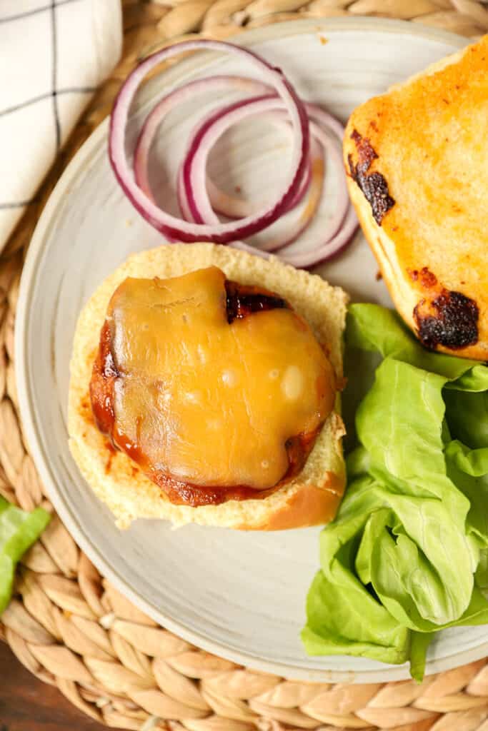 overhead shot of an open faced chicken burger showing the melted Gouda, sliced red onion, and bibb lettuce. 
