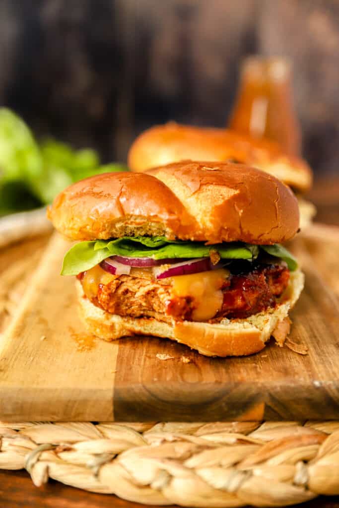 close shot of one of the BBQ chicken burgers with a bite taken out showing the burger texture.