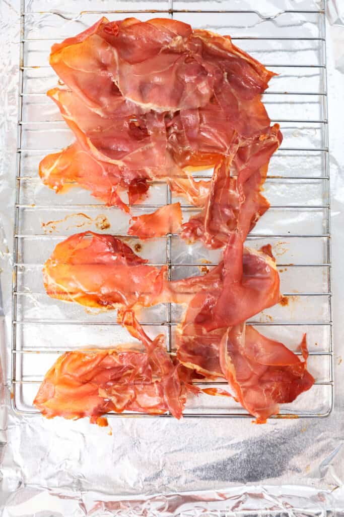 crispy baked prosciutto on the baking rack on a foil lined baking sheet.