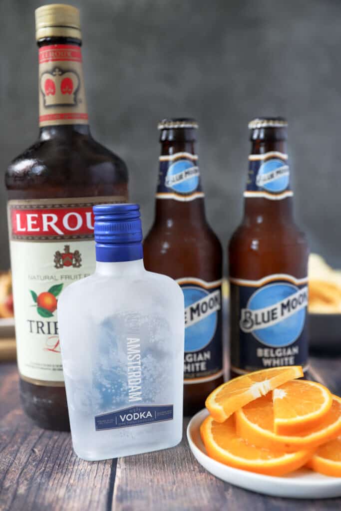 ingredients: bottles of triple sec, Blue Moon beer, vodka, and fresh orange slices.