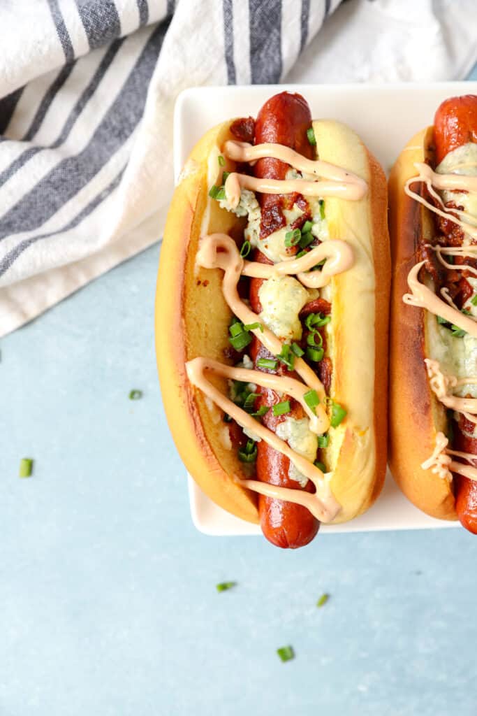 overhead shot of the blue cheese hot dogs on a blue surface.