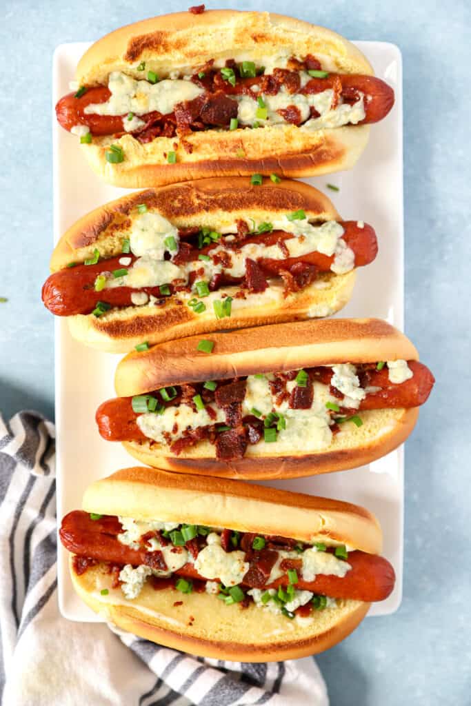 overhead shot of 4 blue cheese hot dogs on a white platter