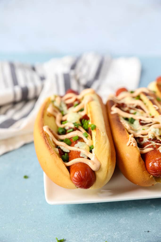 angled shot of the hot dogs drizzled with BBQ mayo and diced chives.