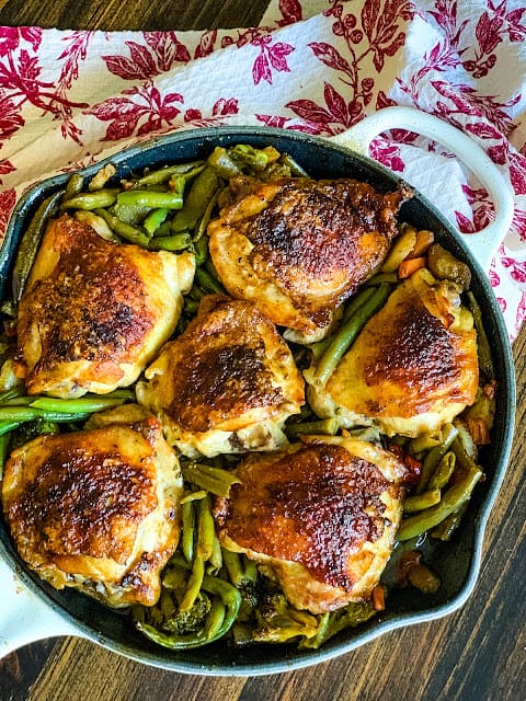 overhead shot of 6 chicken thighs in a pan with green beans.