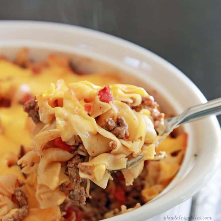 spoon scooping the noodle casserole from a white casserole dish